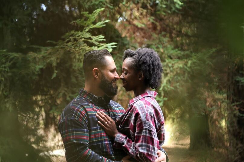 Black female, white male couple holding one another in the woods Columbus Ohio