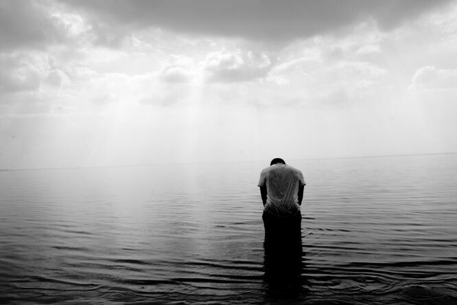 Image of person kneeling in ocean in black and white