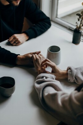 Image couple holding hands on a table with a shared coffee cup