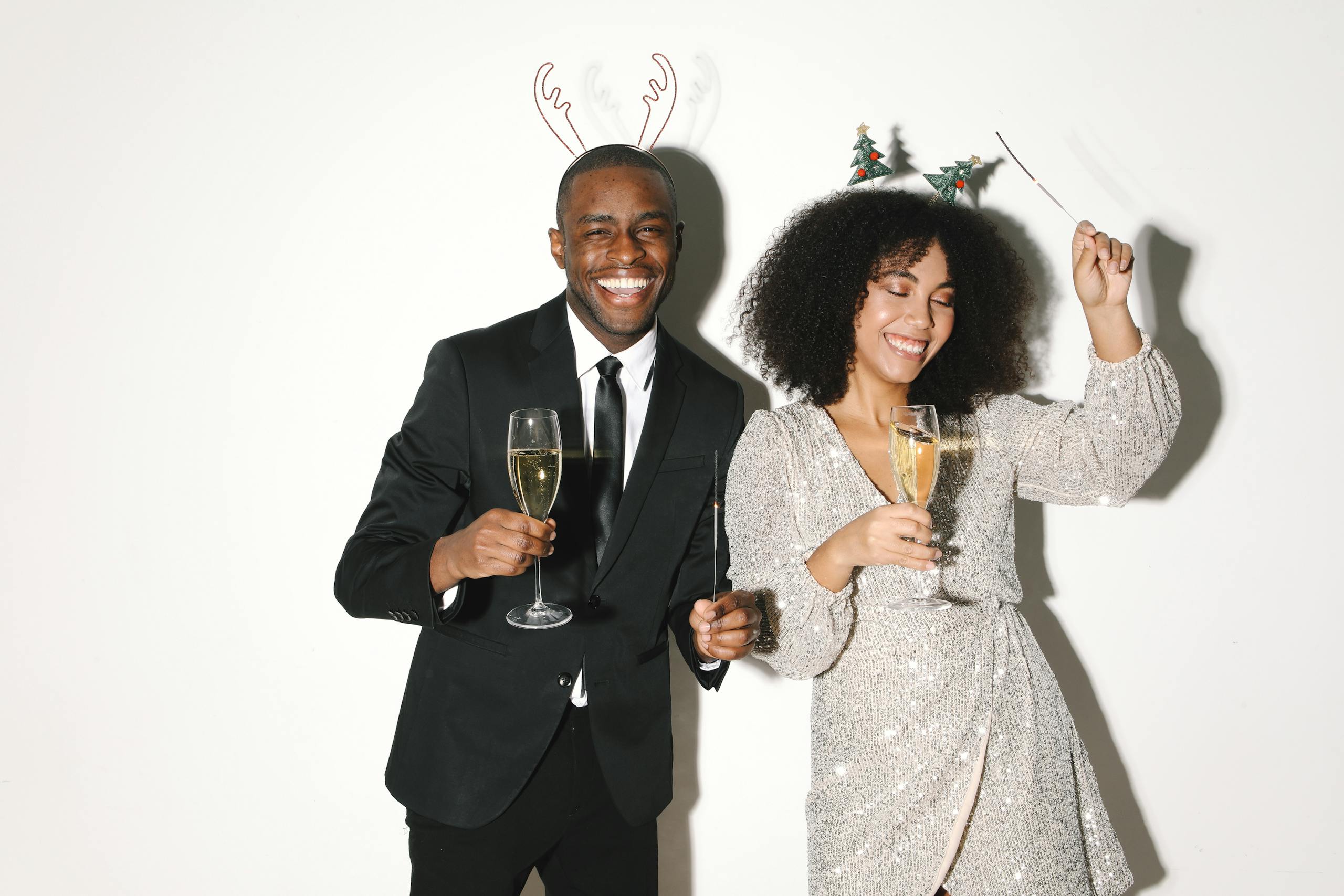 A joyful celebration with two people toasting with champagne, wearing festive attire.