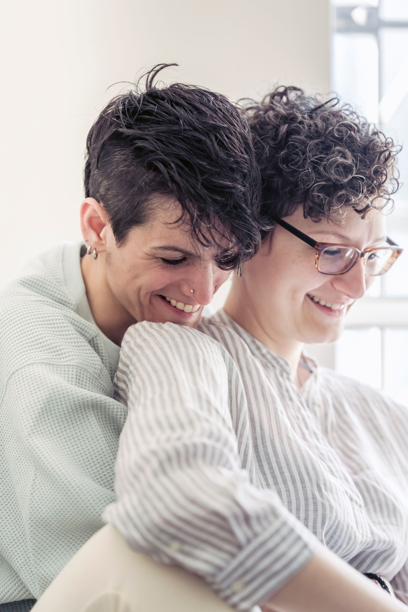 A happy LGBTQ couple shares an intimate moment, enjoying each other's company indoors in soft natural light.